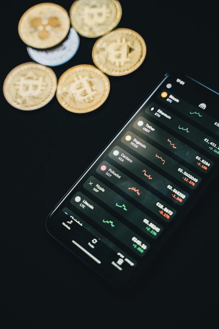 Coins scattered near smartphone with financial charts on screen